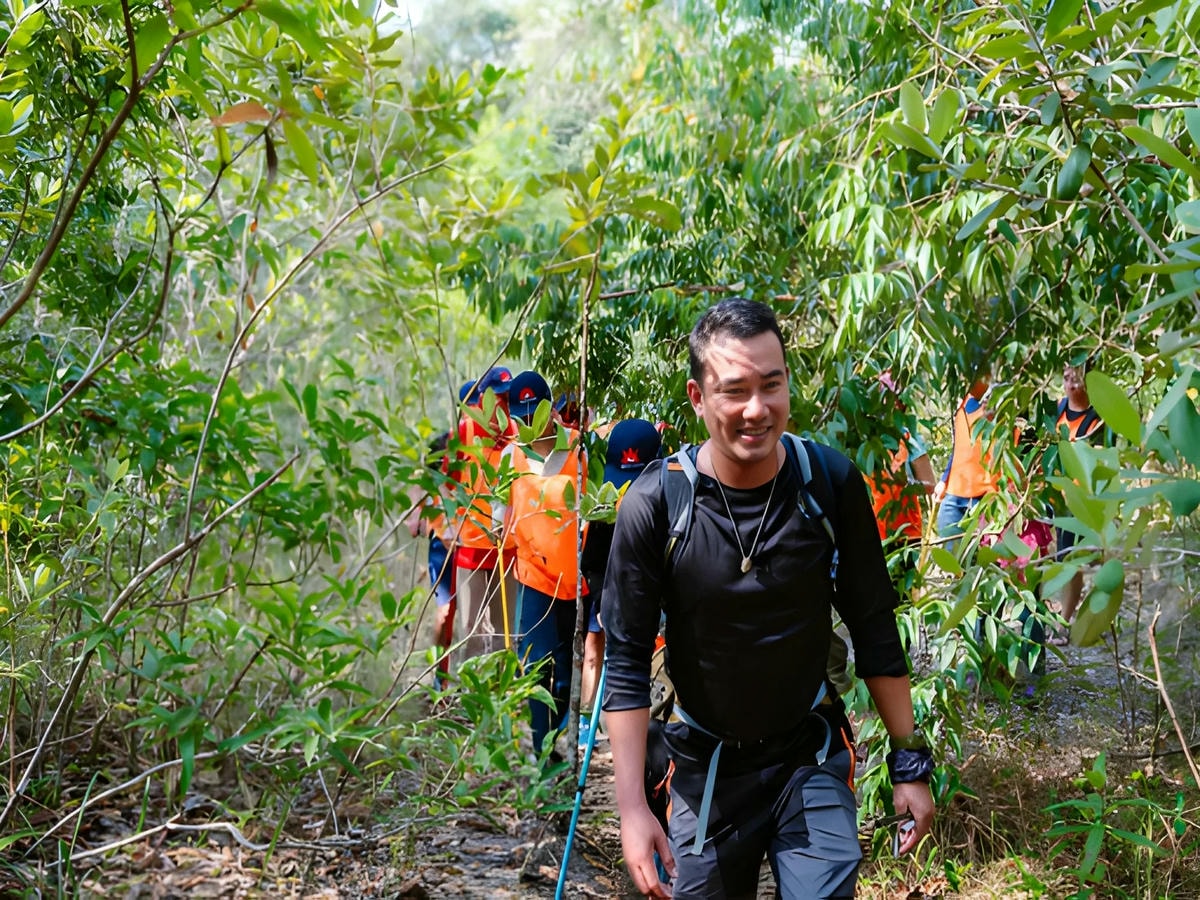 Nhóm du khách trekking cẩn thận di chuyển theo lối mòn trong rừng.