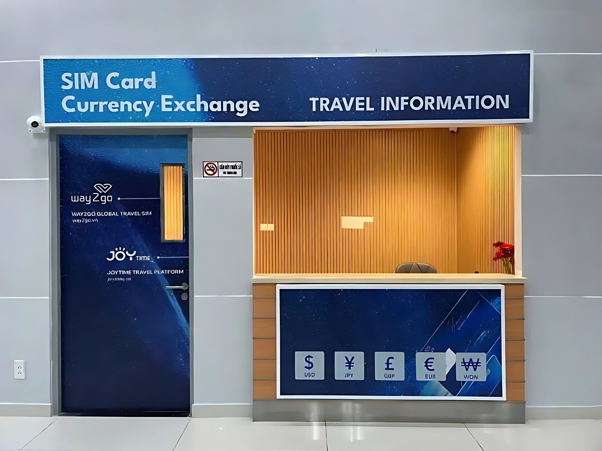 Travelers exchanging currency and purchasing SIM cards at counters in the airport arrivals hall.