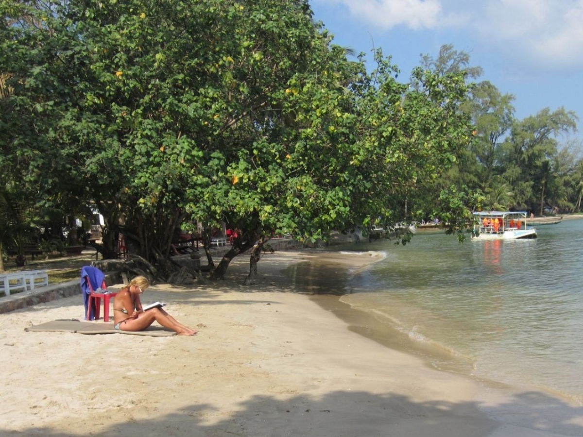 Du khách ngồi trên bờ cát tắm nắng, thư giãn và tận hưởng không khí trong lành tại bãi biển Cửa Cạn. 